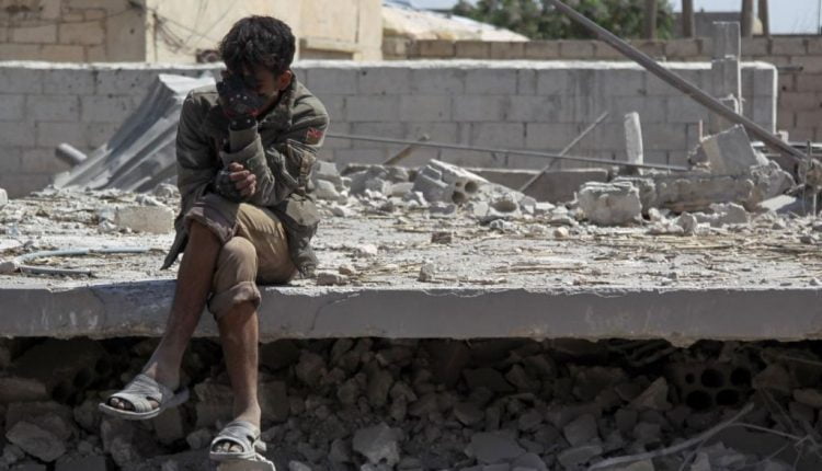 شاب سوري من إدلب يجلس فوق ركام منزل مدمر