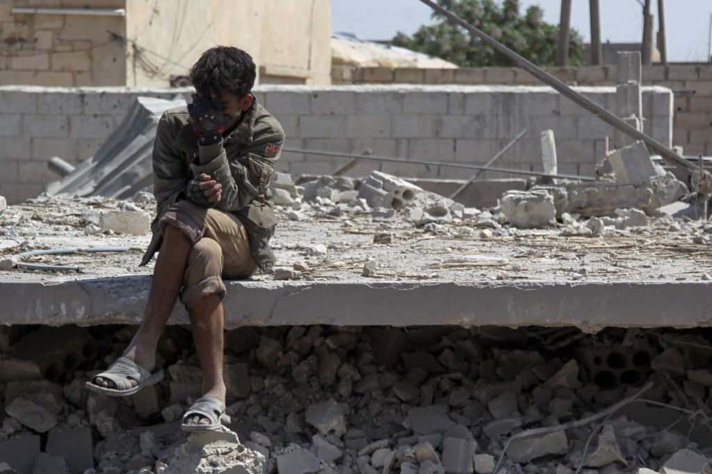شاب سوري من إدلب يجلس فوق ركام منزل مدمر