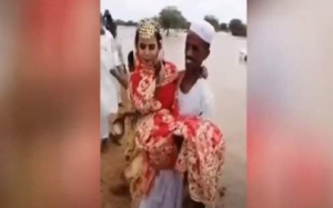 فيديو.. سوداني يتحدى السيول ويحمل عروسه